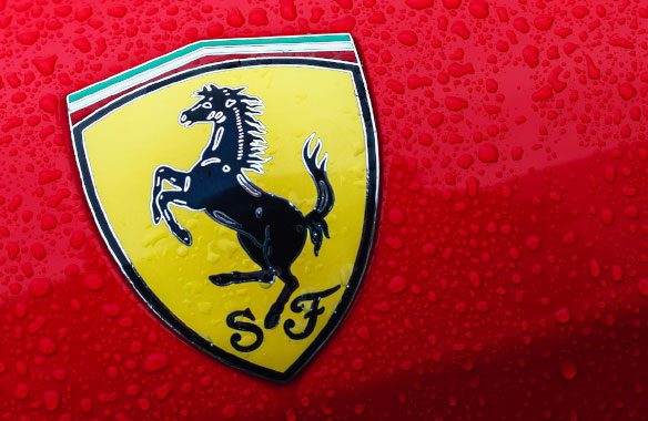 Ferrari Logo: close-up of horse graphic on yellow icon logo displayed on red car.